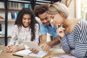 Resultado FIES 2023: três estudantes jovens olham para tela de um tablet enquanto acessam o resultado do Fies.
